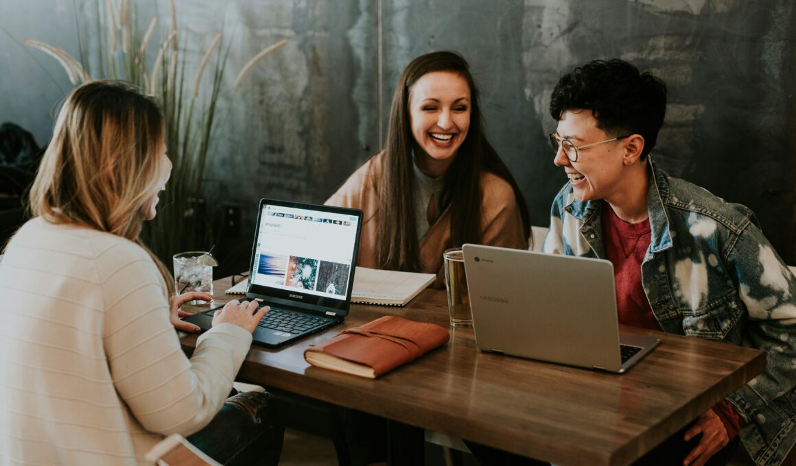 two women and a men with two laptop on a table